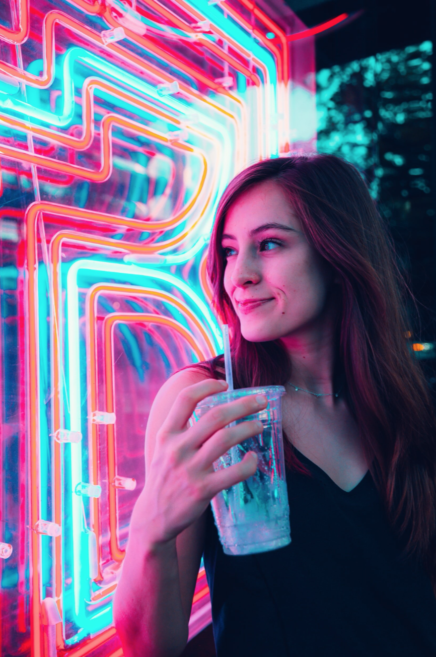 smiling woman next to neon sign